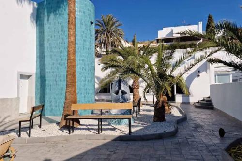 a bench sitting next to palm trees and a building at Gaviotas Beach Golf in Almerimar