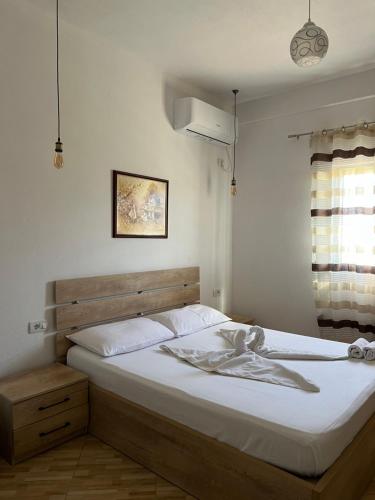 a bedroom with a bed with white sheets and a window at Hotel Apostoli in Përmet