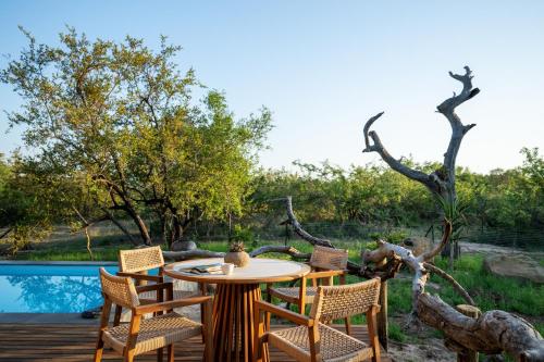 um pátio com uma mesa e cadeiras e uma piscina em Jabulani Safari em Reserva de Caça Kapama
