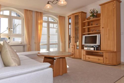 uma sala de estar com um sofá branco e uma televisão em Residenz Bismarck, Whg 11 em Westerland