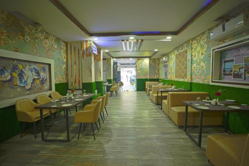 Q Saina S K Regency Rishikesh في ريشيكيش: غرفة طعام بها طاولات وكراسي وجدران خضراء