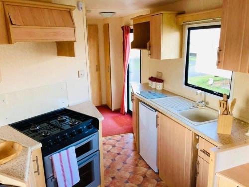 a small kitchen with a stove and a sink at MDL Holiday Let in Rhyl