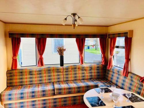 eine Couch mit zwei Tischen vor einem Fenster in der Unterkunft MDL Holiday Let in Rhyl