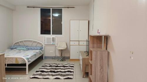 a bedroom with a bed and a desk and a window at Tranquil Cool Studio Condo Mactan Cebu in Lapu Lapu City