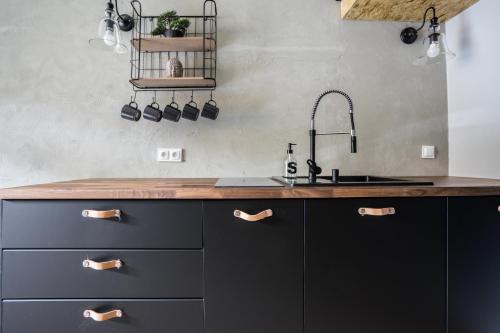 a kitchen with black cabinets and a sink at GA- Cozy Studio - Praga&Ząbkowska in Warsaw