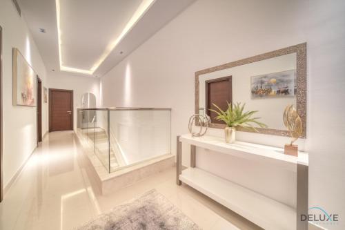 a hallway with white walls and a large mirror at Grand 4BR Villa with Assistant's and Driver's Room Al Dana Island Fujairah by Deluxe Holiday Homes in Fujairah