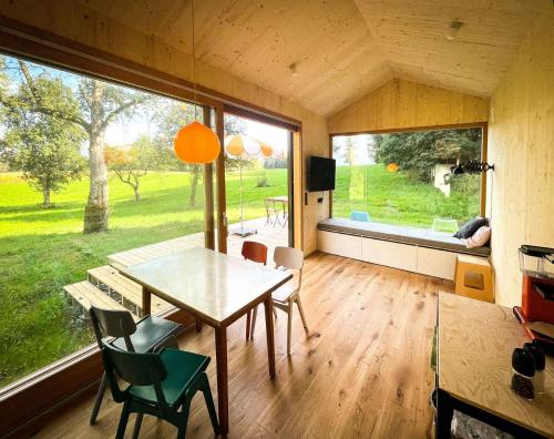ein Esszimmer mit einem Tisch und Stühlen sowie einem großen Fenster in der Unterkunft Die Klingerei - Tiny House Wiese in Pettighofen