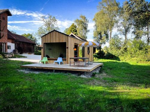 un pequeño cobertizo con una mesa y una sombrilla en Die Klingerei - Tiny House Wiese en Pettighofen