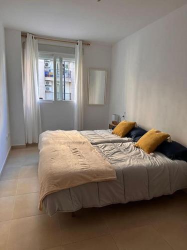 1 dormitorio con 1 cama grande con almohadas amarillas en Piso en Gandía, en Gandía