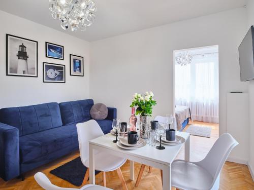 a living room with a table and a blue couch at Villa Łeba II - Loft Apartments in Łeba
