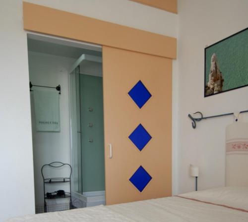 a bedroom with a bed with blue squares on the wall at Nughe 'e' Oro Guesthouse in Nuoro