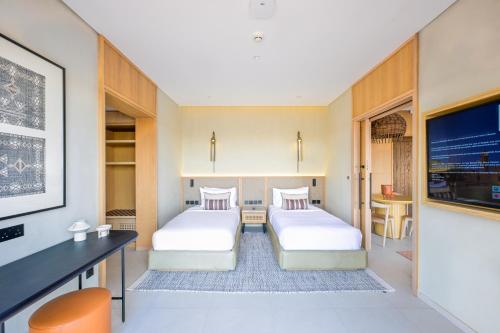シャルジャにあるAl Badayer Retreat by Sharjah Collectionのデスク、テレビが備わる客室で、ベッド2台を利用できます。