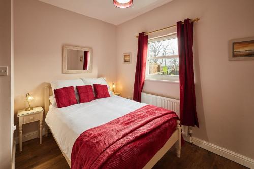 a bedroom with a bed with red pillows and a window at Host & Stay - Gas Light Cottage in Ripon