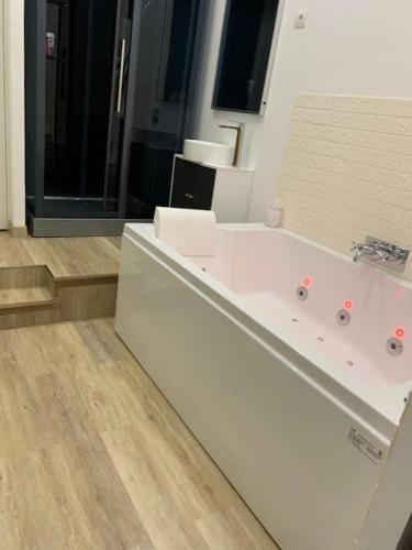La salle de bains est pourvue d'une grande baignoire blanche. dans l'établissement Appartement Spa - NAHLEO Scandinave, à Dole