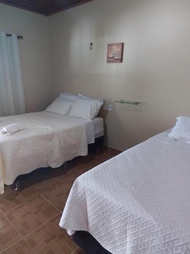 2 camas en una habitación con sábanas blancas en Pousada Sossego Ronaldo e Clarinha, en Alter do Chao