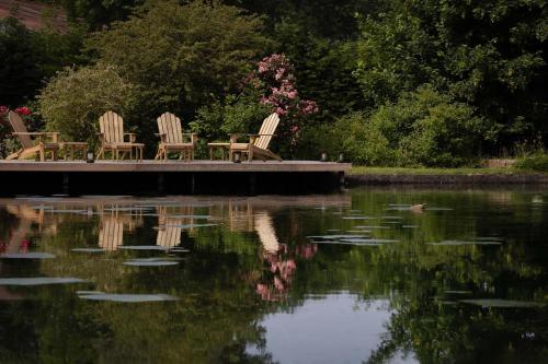 Moulin Moulin Maison d'Hôtes في Dannes: ثلاثة كراسي جالسين على رصيف بجانب البحيرة