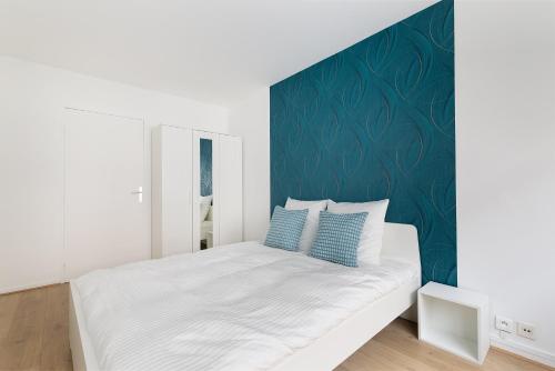 a bedroom with a white bed with a green accent wall at Duplex Cosy 6 personnes - Parking Gratuit - 15 min Centre de Paris Metro 13 in Asnières-sur-Seine