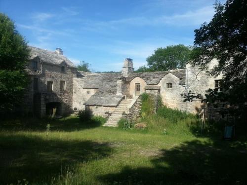 un ancien bâtiment en pierre dans un champ d'herbe dans l'établissement Gîte éco-responsable exceptionnel pour 6 ou 8 personnes secteur gorges du Tarn, à Le Recoux