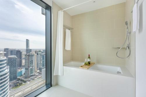 bagno con vasca e finestra con vista di Frank Porter - Vida Residences a Dubai