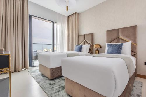 two beds in a hotel room with a large window at Frank Porter - Vida Residences in Dubai