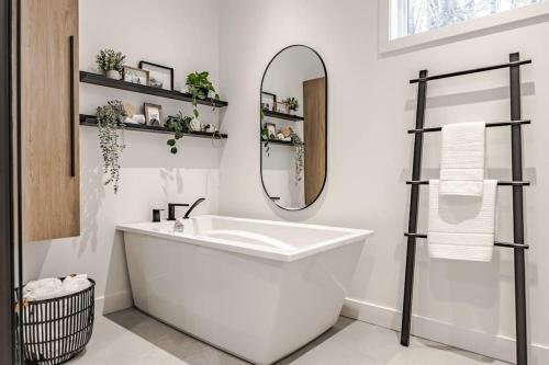 een witte badkamer met een bad en een spiegel bij Légendaire Private Hot Tub Game room in Brownsburg