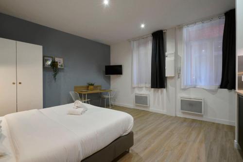 une chambre avec un grand lit blanc et un bureau dans l'établissement Equipped studio in the heart of the stations, à Lille