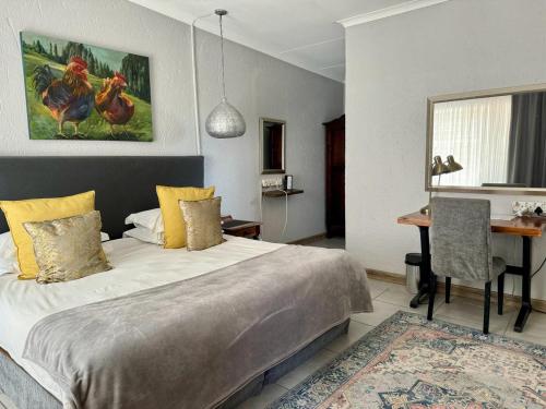 a bedroom with a bed and a table and a desk at Rabbit Hole Hotel in Krugersdorp