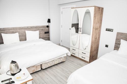 a bedroom with two beds and a mirror at Begonvil Pansiyon in Çanakkale