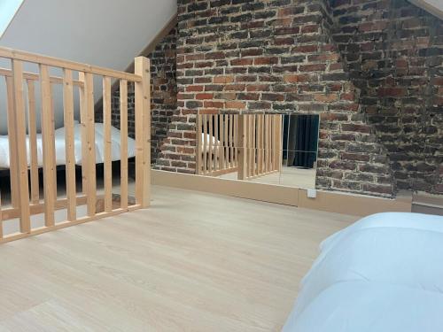 a bedroom with a brick wall and a crib at Maison Cosy 5 chambres 3 SDB proche Lille in Roubaix