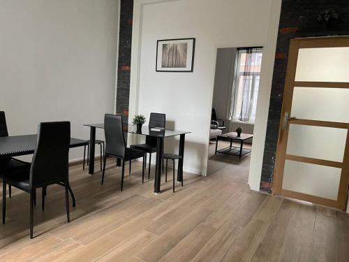 une salle à manger avec une table et des chaises noires dans l'établissement Maison Cosy 5 chambres 3 SDB proche Lille, à Roubaix
