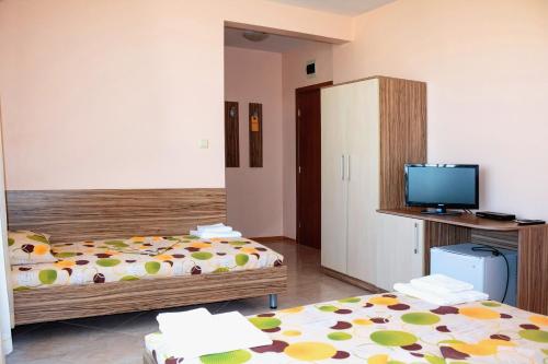 a room with two beds and a desk and a tv at Guest House Moiata Kashta in Chernomorets