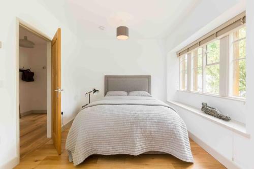 a white bedroom with a bed and a window at Classic Cotswolds Apartment, The Little Coach House in Blockley