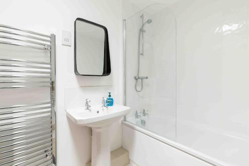 a white bathroom with a sink and a shower at Classic Cotswolds Apartment, The Little Coach House in Blockley