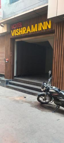 una motocicleta estacionada frente a un cartel del hotel en Vishram Inn, en Alwar