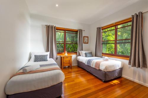 een slaapkamer met 2 bedden en 2 ramen bij Cedia at Byron Bay Hinterland in Byron Bay