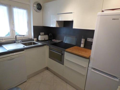 La cuisine blanche est équipée d'un évier et d'un réfrigérateur. dans l'établissement Appartement Cannes Ferrié, à Cannes