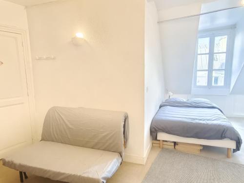een slaapkamer met een bed, een bank en een raam bij Appartement 4 personnes au centre Paris - Chatelet in Parijs