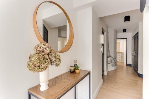 a mirror and a vase with flowers on a table in a hallway at Palais des congrès , 4 bedrooms in Levallois-Perret