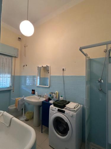 ein Badezimmer mit einer Waschmaschine und einem Waschbecken in der Unterkunft Sotto il cielo di Ulisse in Sabaudia