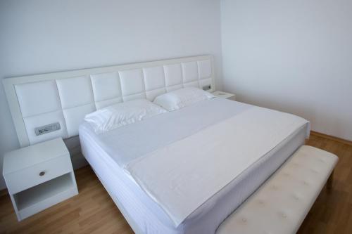 a white bedroom with a white bed and a nightstand at Sunset - The Twin Villa in Široka