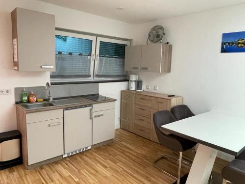 a kitchen with white cabinets and a table and chairs at Bungalow am Donaupark in Regensburg