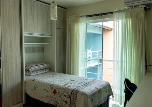 um quarto com uma cama e uma grande janela em Casa de Alto Padrão próxima ao Beto Carrero em Navegantes