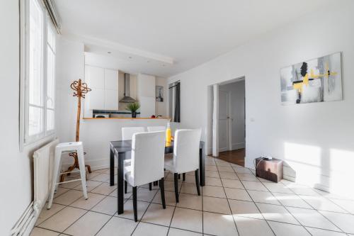 une salle à manger avec une table noire et des chaises blanches dans l'établissement Appartement Paisible Proximité des Halle - 4P - FLAT-GUEST, à Paris