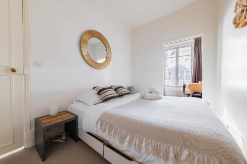 - une chambre blanche avec un lit et un miroir dans l'établissement Appartement Paisible Proximité des Halle - 4P, à Paris