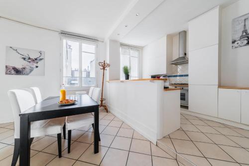 une cuisine avec une table noire et des armoires blanches dans l'établissement Appartement Paisible Proximité des Halle - 4P, à Paris