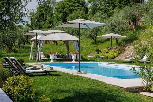 a swimming pool with umbrellas and lounge chairs next to a pool at CORTE SAGGIN Charme Relais in San Pietro in Cariano