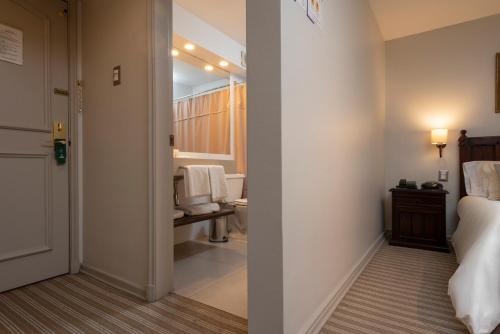 1 dormitorio con 1 cama y baño con lavamanos en Teclados Hotel, en Santiago