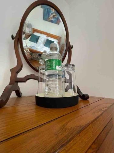 Eine Flasche Wasser steht auf einem Tisch vor einem Spiegel. in der Unterkunft Hendrix’s cottage in Lincoln