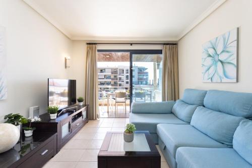 un salon avec un canapé bleu et une télévision dans l'établissement Balcon los Gigantes Beautiful, à Puerto de Santiago