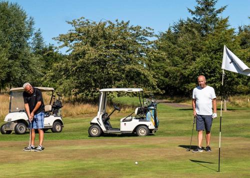 dos hombres jugando al golf con un carrito de golf en Percy Wood Country Park en Morpeth